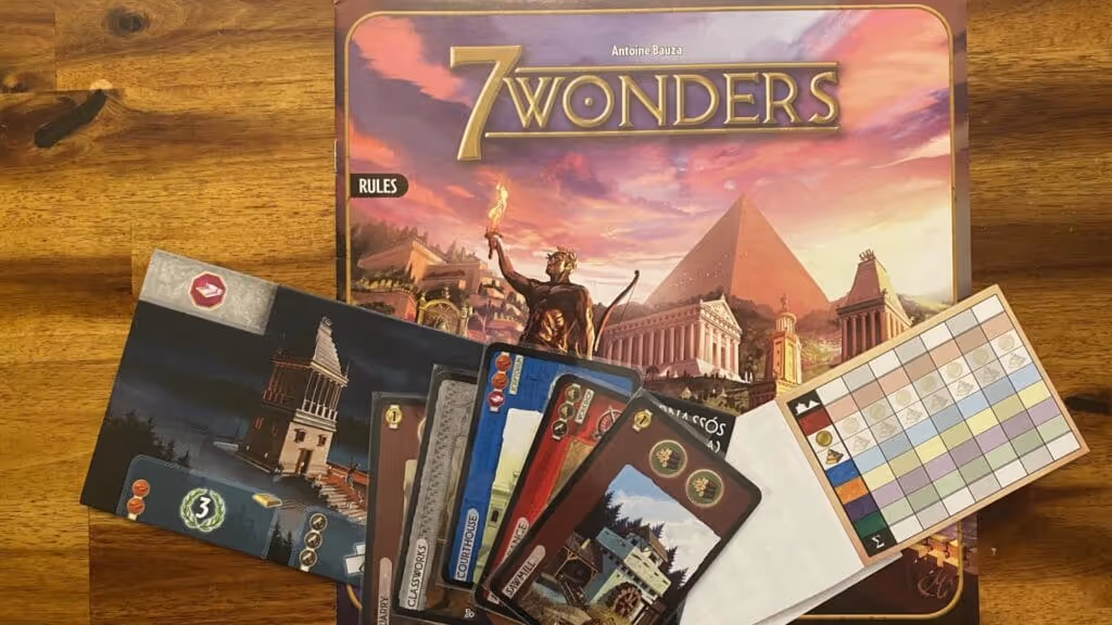 7 Wonders board game box, Wonder boards, resource cards, and score sheet displayed on a wooden table.